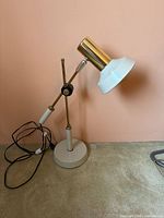 Full view of adjustable brass and white desk lamp on base with cord