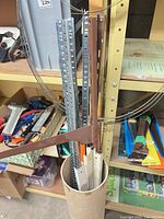 Tube holding slotted uprights of varied colours with a brown shelf bracket visible