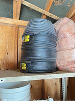 Two stacked rolls of black ribbed plastic edging on shelf