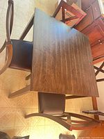 Top view of table and part of chairs, shows wood grain and seat material