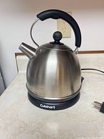 Overall view of Cuisinart stainless steel electric kettle on its base, cord visible