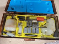 open kit showing push drill, bits, accessories in yellow tray within marbled case