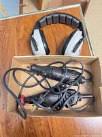 Two Craftsman rotary tools with cords inside cardboard box and gray/black earmuffs