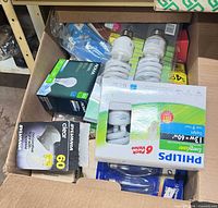 Open box showing Philips 6-pack, Sylvania pack, NOMA box, loose spiral CFL bulbs