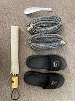 All items laid out: umbrella, shoehorn, woven slippers, Puma slides