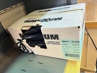 Opened Maxxium box showing black garbage bags inside