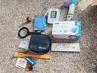 All items laid out including BP monitor, masks, batteries, hair dryer, magnifier, cleaning kit, accessories