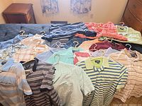 Assorted men’s medium shirts and pants laid out on bed