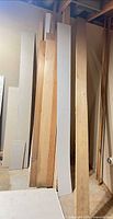Bundle of various length boards, sheet goods and trim leaning against wall