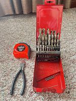 Overall view showing drill bit box open, tape measure, pliers