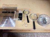 All items laid out: sheet, two handheld magnifiers, two pocket magnifiers, boxed loupes, pouch