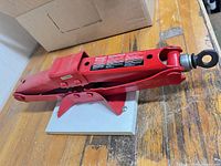 Full view of red MotoMaster scissor jack on table