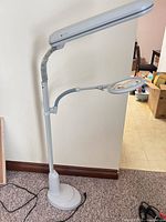 Full view of OttLite gray floor lamp showing base, gooseneck, magnifier arm and lamp head