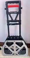 Folded Pack-n-Roll hand truck front view showing handle, frame and wheels
