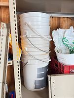 Stack of five white plastic buckets showing handles and overall condition
