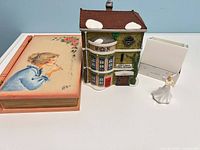 Grouped view of figurine, Dickens’ Village building, painted wooden box