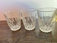 three clear diamond-cut glass tumblers side by side