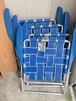 Four folded blue aluminum lawn chairs stacked together