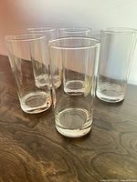 Five clear highball glasses on wooden surface