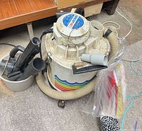 Vacuum with hose, attachments in bucket, filter bag set