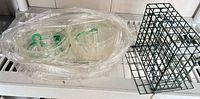 Lot overview showing stack of clear plastic saucers in bag and green metal suet cage on shelf