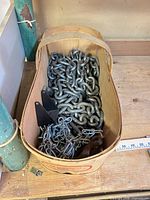 Basket containing heavy steel chain, lighter chain, brackets and anchor plate