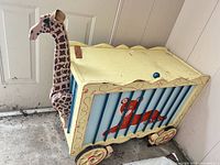 Full view of toy chest showing giraffe head, wheels, tiger motif, overall wear