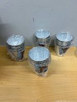 Stacks of small galvanized metal buckets sealed in plastic wrap on table