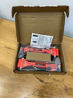 Open box with two red Amazon Basics safety tools in plastic bags and instruction sheet