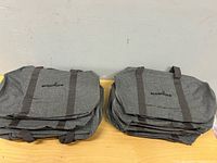 Two stacks of grey Accenture duffel bags showing exterior and logo