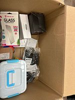 View of box showing screen protector packaging, storage case, black strap, black box