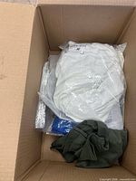 Overall view of box showing white garment, green fabric