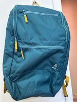 Front view showing Woods logo, teal fabric, yellow zipper pulls, main and front compartments