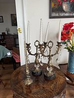 two gilt three-arm candelabra and one gilt single candlestick on table