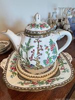 Teapot on matching tray showing floral pattern and gilt accents