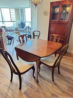 Dining table with four chairs arranged around it, showing overall style and condition