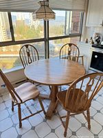 Full view of round oak table with four matching chairs