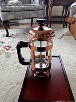 Full view of copper French press on wooden box lid