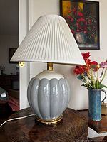 Full view of blue ceramic table lamp with pleated shade on table
