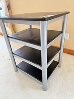 Front angled view showing four black shelves and silver legs