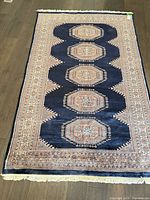Full view of navy rug with medallions and fringe