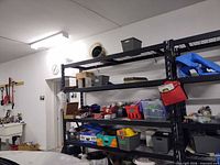 Metal shelving with multiple storage bins, cleaning supplies, umbrella, miscellaneous household items