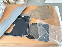 Multiple car floor mats of various colours and cargo cover laid out