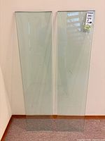 Front view of two clear glass panels standing against wall