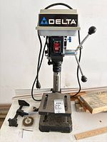 Front view of Delta 11-900 drill press on workbench with accessories visible