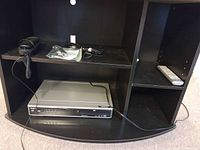 Front view Symphonics CSHG80P DVD player on shelf with cords and handset