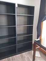 Front view of dark laminate bookcase showing twin columns and adjustable shelves