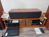 Front view of entertainment stand with speaker placed on top; shows overall design, doors, shelves