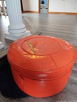 Overall view of orange round ottoman with slipcover underneath
