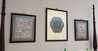 Three framed textile prints hanging side by side on wall